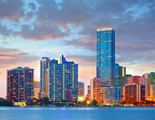 Fototapeta premium Miami Florida USA, sunset or sunrise over the city skyline of downtown business and residential illuminated buildings, with colorful clouds and reflections in the water of Biscayne Bay,