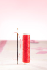 Stehende Nähnadel mit rotem Faden
