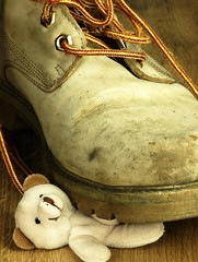 Teddy bear crushed by a heavy, old military boot.