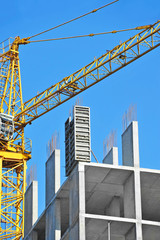 Crane and building construction site against blue sky