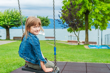 Outdoor portrait of a cute little girl on a swing