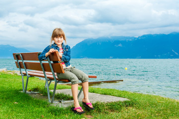 Pretty little girl resting by the lake