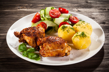 Barbecued chicken legs with boiled potatoes and vegetables
