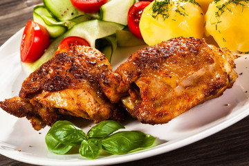Barbecued chicken legs with boiled potatoes and vegetables