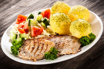 Grilled steaks, boiled potatoes and vegetable salad