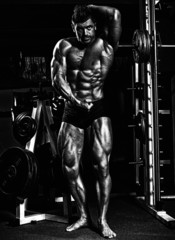 Fototapeta na wymiar fitness shaped muscle man posing on dark gym