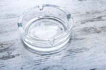Empty glass ashtray on a wooden table.