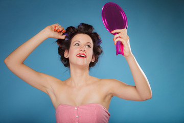 girl styling hair with curlers looking in the mirror
