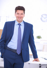 Confident successful young businessman leaning arms on his desk