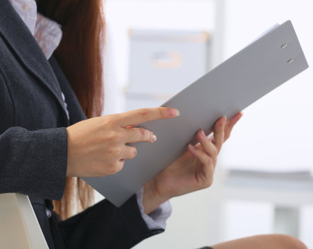 Young happy businesswoman in office holding a folder