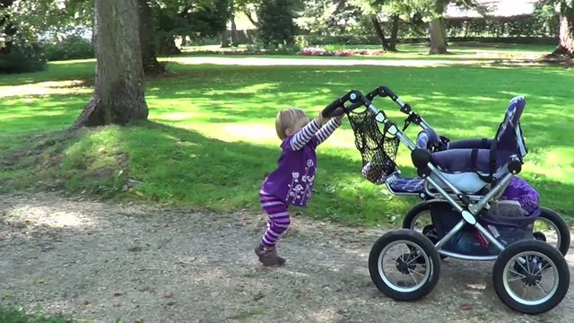 Kind spielt mit Kinderwagen