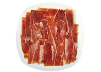 Serrano ham slices on a white dish. Jabugo. Spanish tapa.
