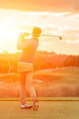 Golf player tee off at sunset