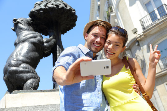 Tourists taking selfie photo by bear statue Madrid