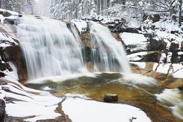 Freeze winter day at cascade of waterfall on mountain river. 