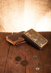 Vintage books and coins and spectacles on old wooden table. Tone