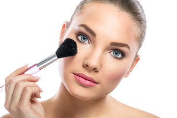 young woman with mirror applying powder on cheek