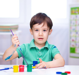 Little boy is playing with paints