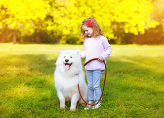 Naklejka na ściany i meble Happy positive little girl and dog having fun outdoors