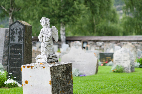 Gravestone statue of praying angel at cemetery