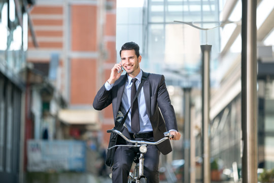 Businessman riding a bicycle and talking with mobile phone