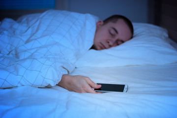 Man sleeping in bed and holding a mobile phone