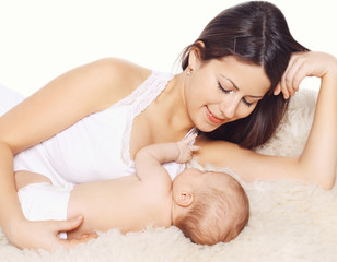Happy young mom and baby lying on the bed at home