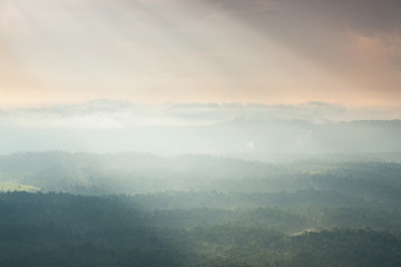 Sunlight shines through the clouds into the mountains and forest