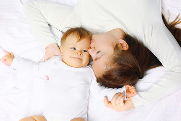 Happy mother and baby lying on bed at home, top view