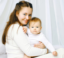Portrait happy mother and baby on the bed at home