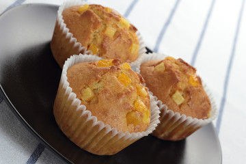 Muffin with orange zest on a black plate.