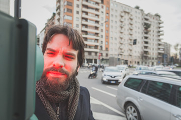 Young handsome bearded man posing in the city streets