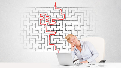 Business woman at desk with labyrinth and arrow