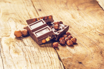 Sweet, milk chocolate with nuts on a wooden rustic table.