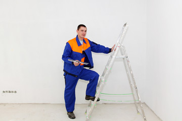 Young plasterer with ladder indoors
