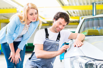 KFZ-Mechaniker kontrolliert Lack in Autowerkstatt