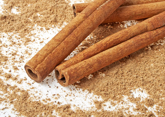 Сinnamon sticks with its dust around it over a white background
