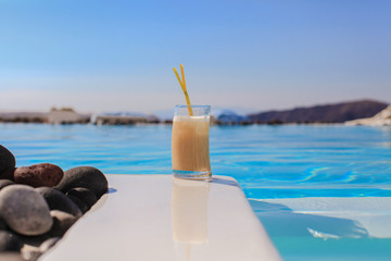 Fototapeta na wymiar Glass with sweet alcohol cocktail near swimming pool