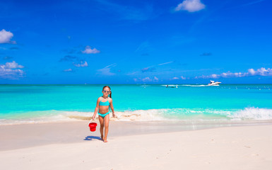 Fototapeta na wymiar Little happy girl playing with beach toys during tropical