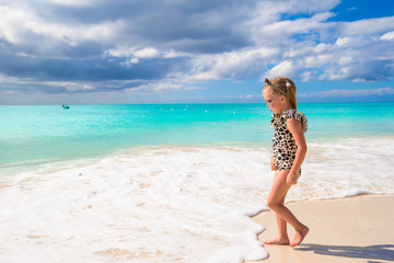 Adorable little girl on white beach during tropical vacation