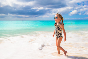 Adorable little girl on white beach during tropical vacation