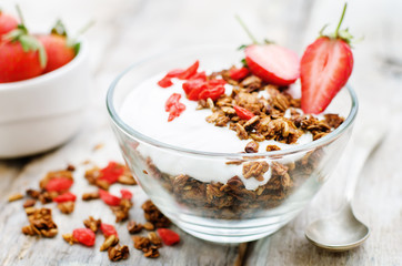 fresh breakfast of granola, yogurt, nuts, goji berries and straw