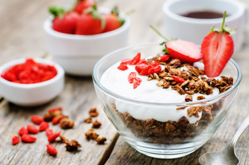 Fototapeta na wymiar fresh breakfast of granola, yogurt, nuts, goji berries and straw