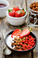 fresh breakfast of granola, yogurt, nuts, goji berries and straw