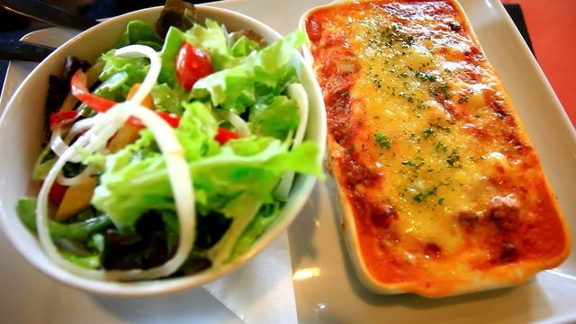 Fresh baked lasagna with vegetable salad. Close up. HD