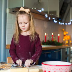 Little girl baking gingerbread cookies for Christmas at home