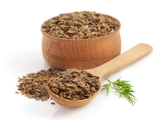 dried dill seeds in bowl on white background