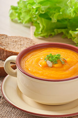 Delicious cream of pumpkin soup in a bowl on wooden table