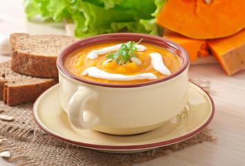 Delicious cream of pumpkin soup in a bowl on wooden table