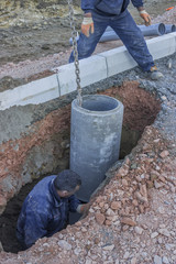 Road worker in trench installing storm drain system